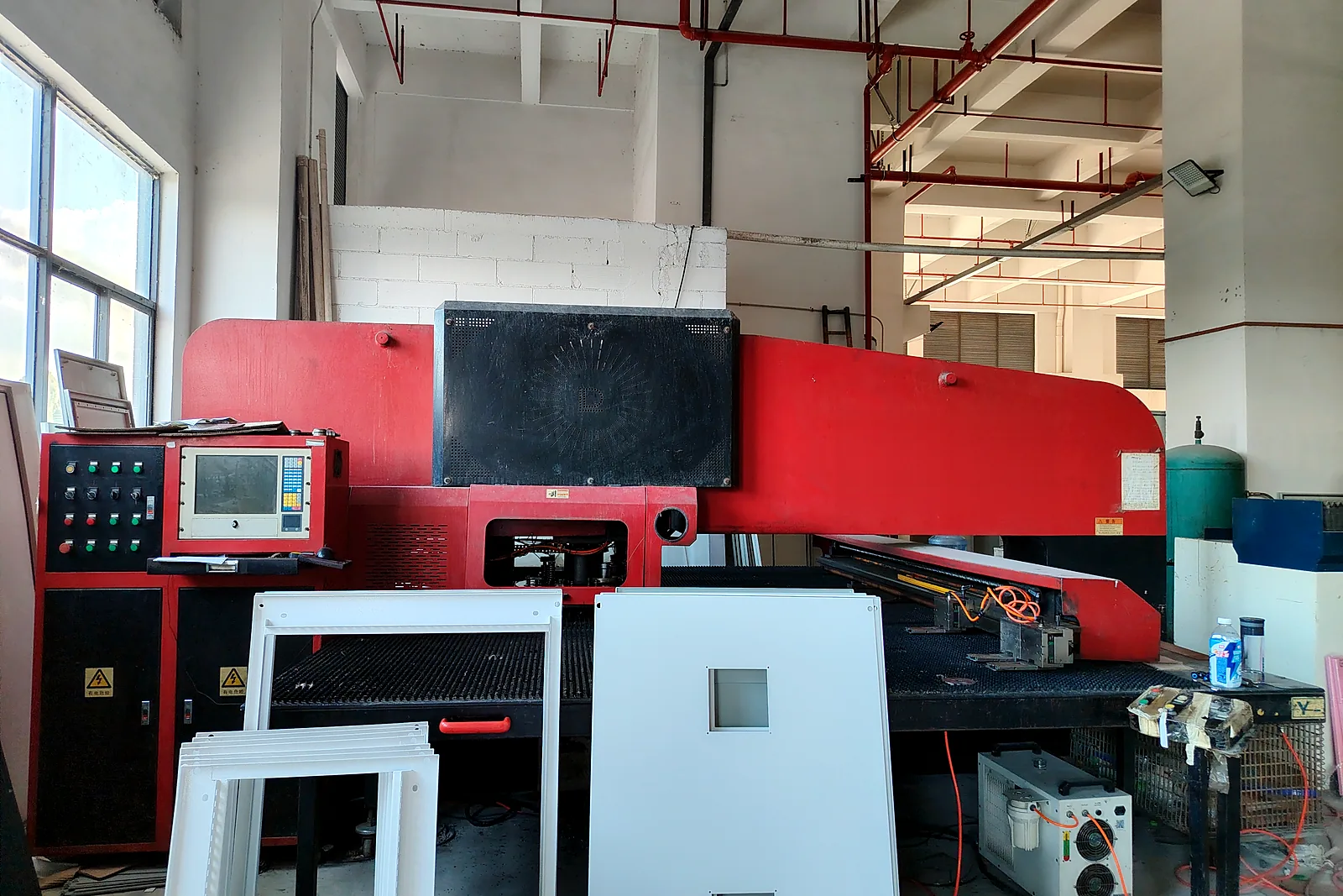 CNC turret punch press with finished white pet wash machine panels stacked in front